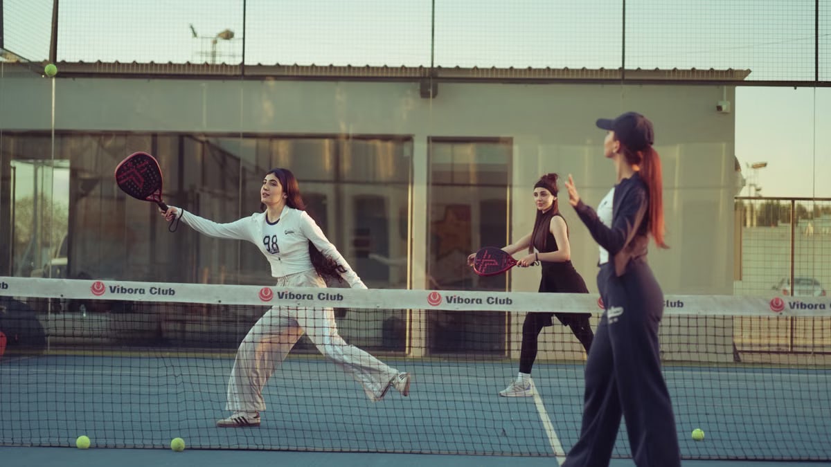Three women enjoying a game of padel on an outdoor court at Vibora Club in Baghdad.