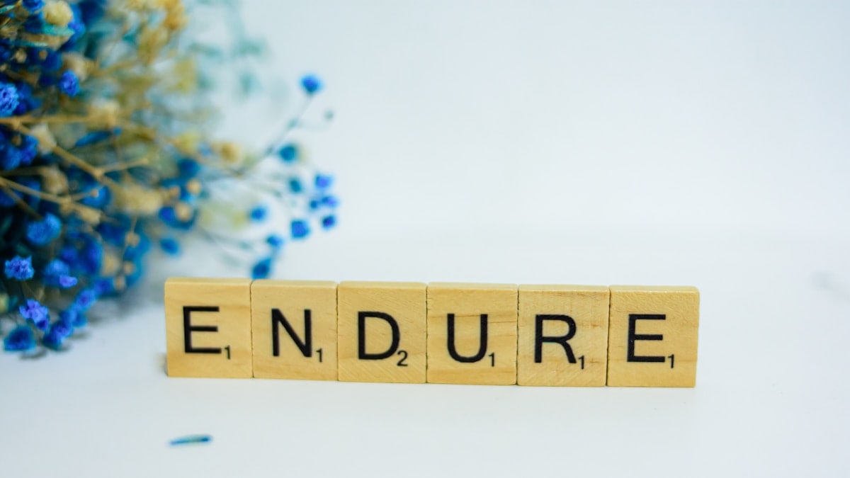 a scrabble type block spelling the word endure